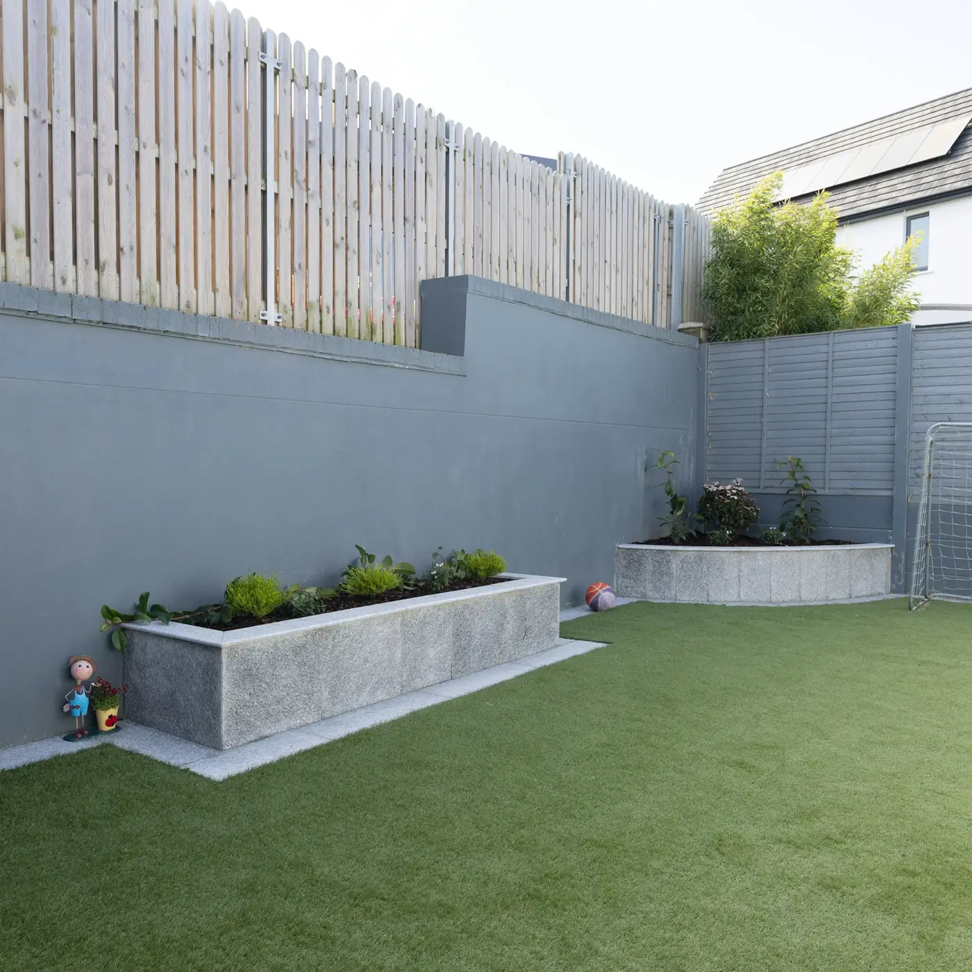 Backyard with artificial grass lawn and raised concrete planters
